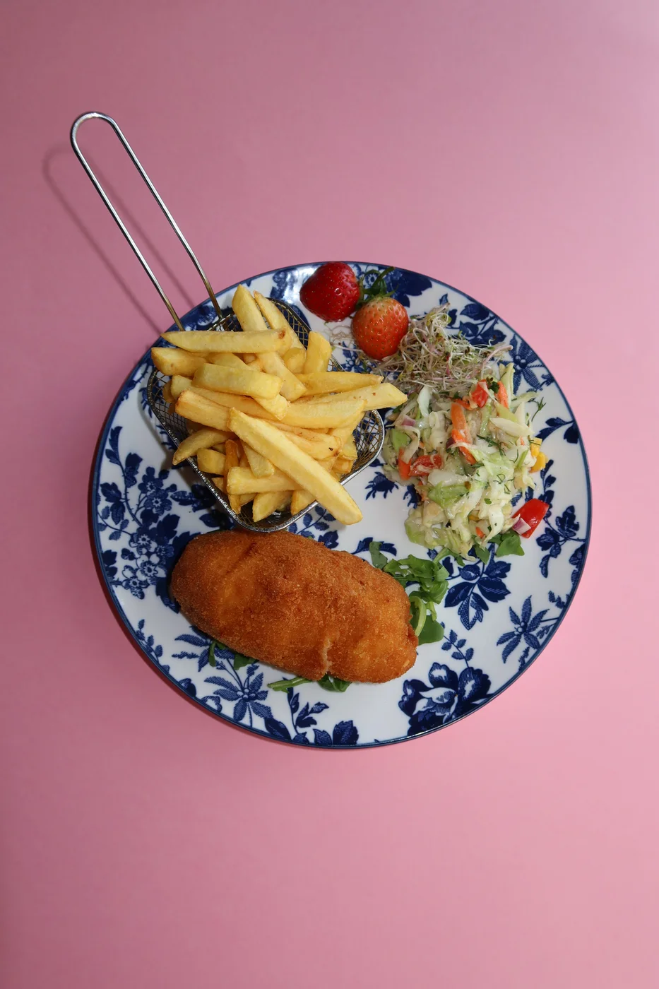 Breaded Chicken Kyiv with chips and salad on a blue-and-white plate