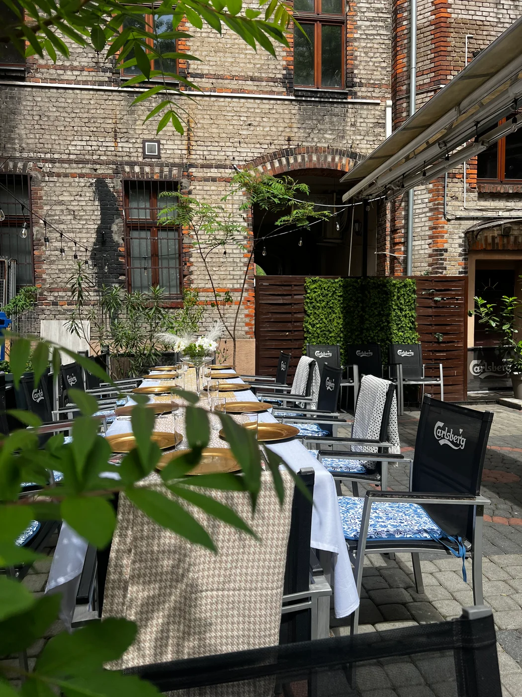 Ein Tisch mit goldenen Platztellern im grünen Backsteinhof von Sorrento