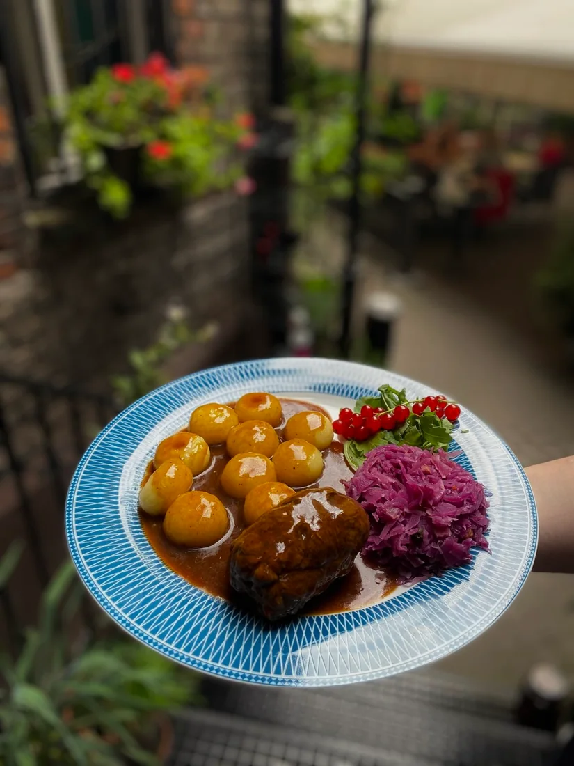 Roulade with gravy, Silesian dumplings and red cabbage on a blue plate