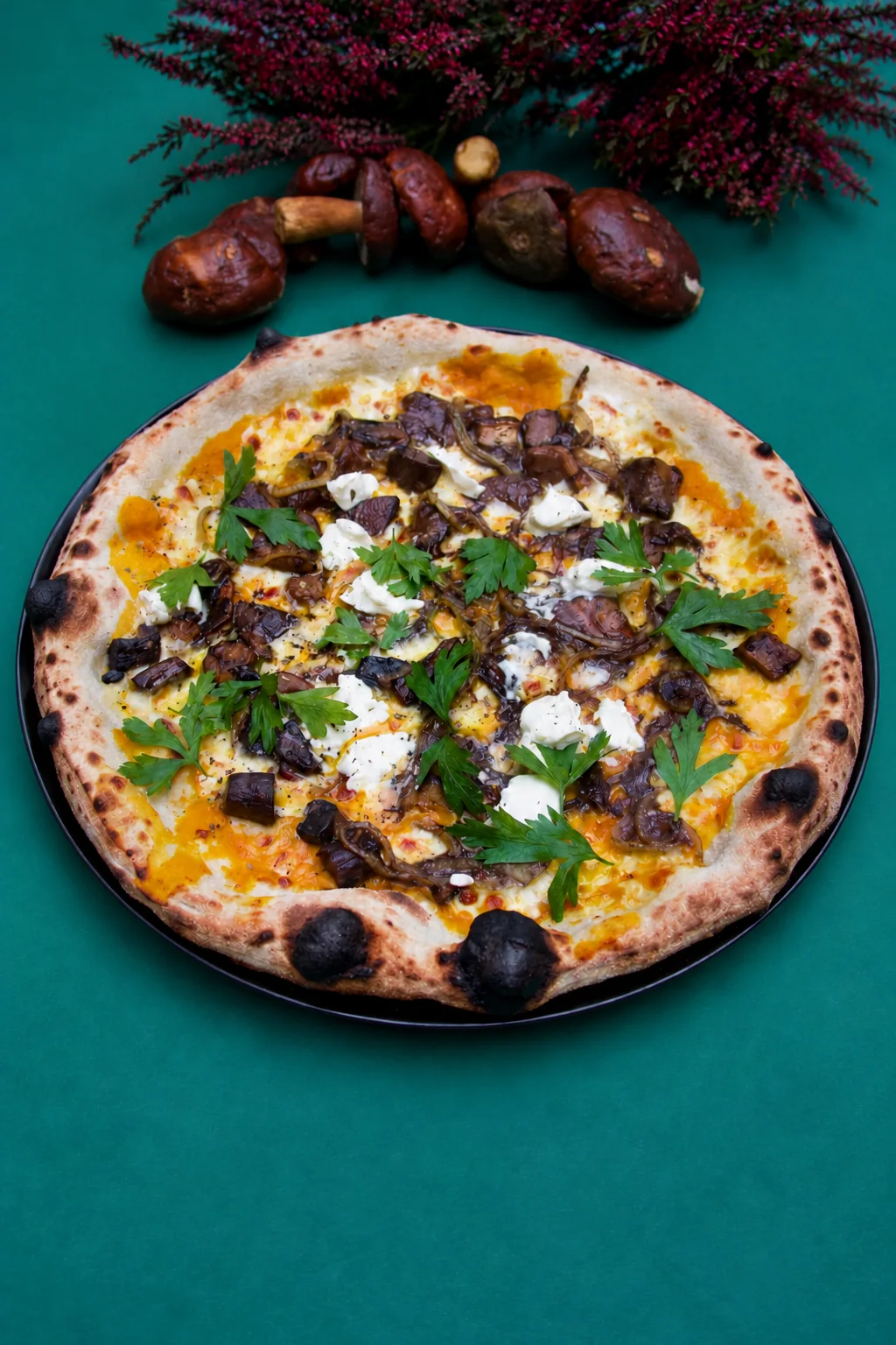 Mushroom pizza with parsley on a dark plate